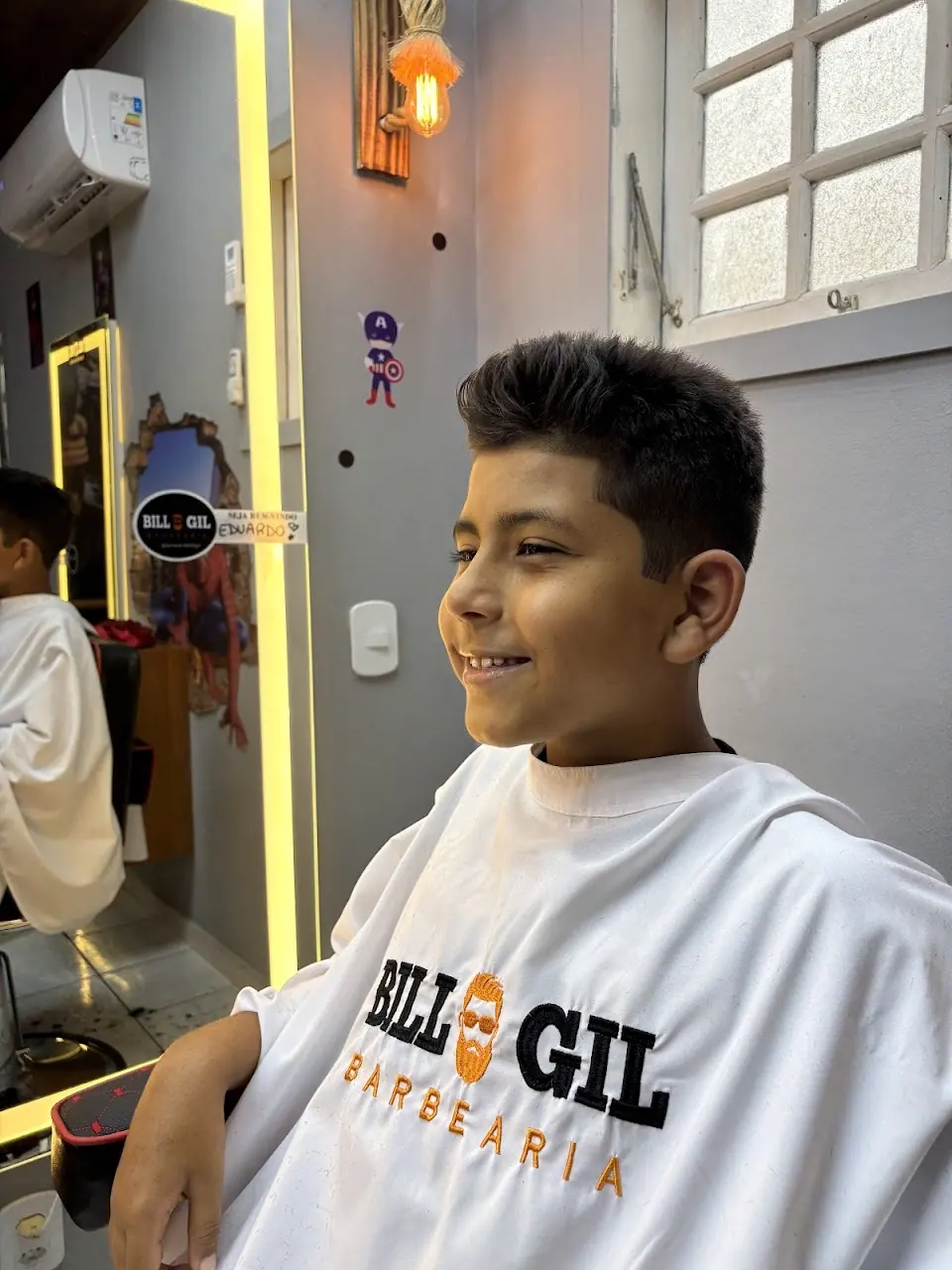 Menino sorrindo depois do corte, de capa da Bill & Gil